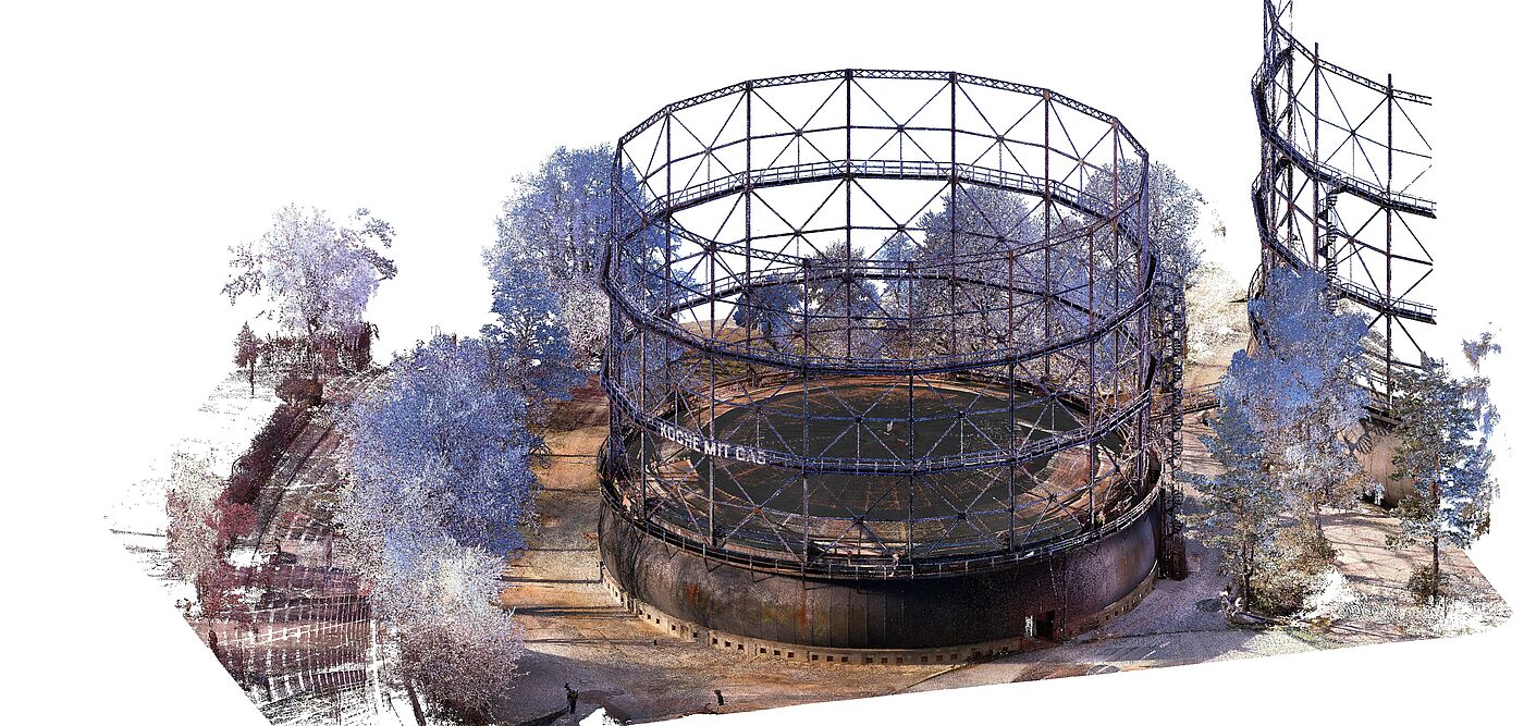 Digitale Punktwolke eines historischen Gasbehälters mit Stahlgerüst. Die 3D-Darstellung zeigt die kreisförmige Struktur des Gasbehälters mit feinen Details der Stahlkonstruktion und der Umgebung, einschließlich Bäumen und Bodenflächen. Rechts ist ein weiteres Teilgerüst zu sehen. Die Punktwolke dient zur präzisen Vermessung und Modellierung für Dokumentation oder Planung.