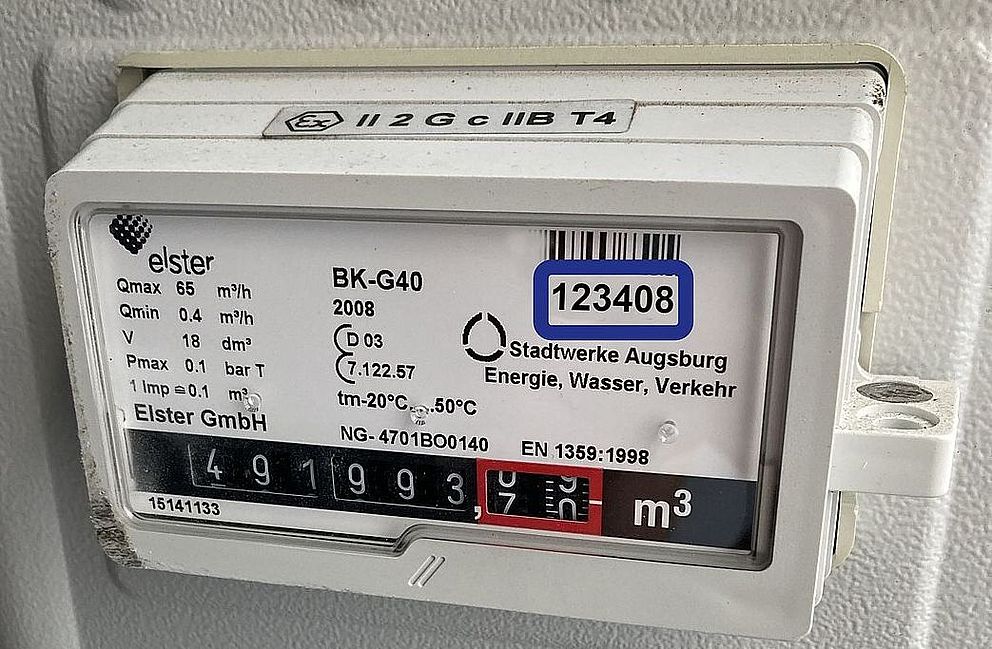 Gaszähler der swa Netze GmbH in Nahaufnahme. Das weiße Messgerät vom Typ Elster BK-G40 ist in einer technischen Anlage montiert. Auf dem Display ist ein aktueller Zählerstand von rund 49.993 m³ ablesbar. Sichtbar sind außerdem technische Kenndaten, eine Inventarnummer mit Barcode (123408) sowie die Beschriftung „Stadtwerke Augsburg Energie, Wasser, Verkehr“. Die Aufnahme dokumentiert die Erfassung und Überwachung von Gasverbrauchsdaten im Netzbetrieb.