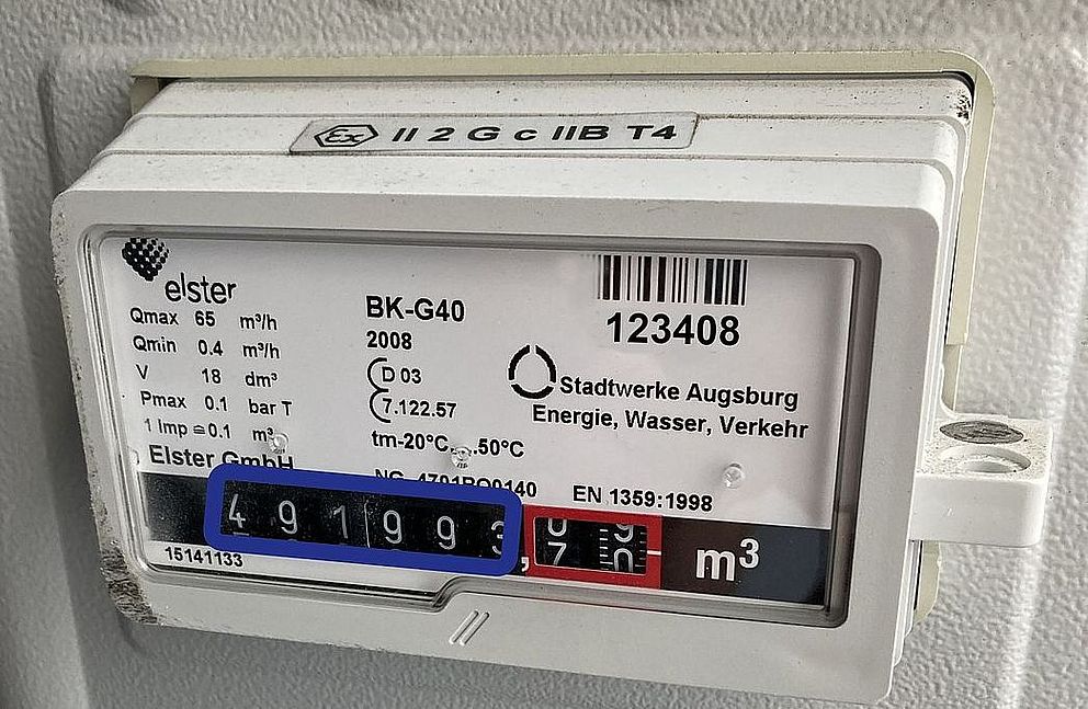Gaszähler der swa Netze GmbH in Nahaufnahme. Das weiße Messgerät vom Typ Elster BK-G40 ist in einer technischen Anlage montiert. Auf dem Display ist ein aktueller Zählerstand von rund 49.993 m³ ablesbar. Sichtbar sind außerdem technische Kenndaten, eine Inventarnummer mit Barcode (123408) sowie die Beschriftung „Stadtwerke Augsburg Energie, Wasser, Verkehr“. Die Aufnahme dokumentiert die Erfassung und Überwachung von Gasverbrauchsdaten im Netzbetrieb.